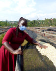 A farmer member of the Agasake Women's Group in Western Rwanda showing their african drying beds with green coffee drying on them