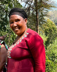 Three women of the Agasake Women standing together with the women's coffee farm in the distance