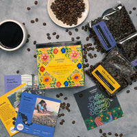 Coffee beans and packages with colorful labels on a gray surface