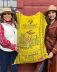 Lilly and Sabrina holding up a bag of green coffee with their branding