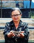 Swelter Coffee's partner Mayra Solis holding up a handful of drying coffee cherries from her drying beds on her farm in Costa Rica