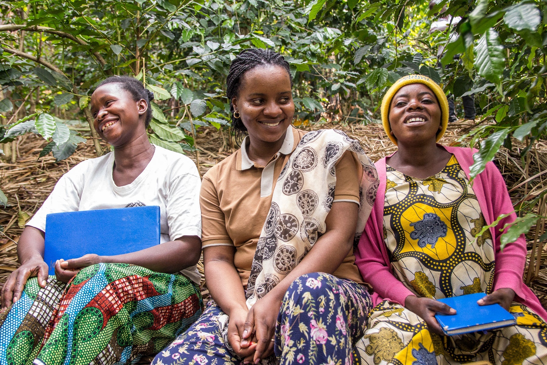 Three women on a coffee farm smiling in the DRC