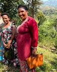 Three women of the Agasake Women standing together with the women's coffee farm in the distance