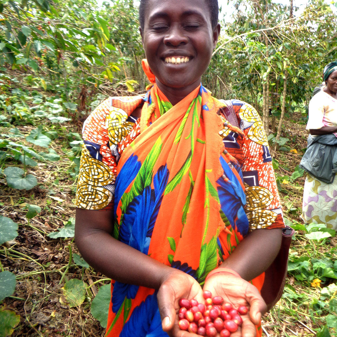 Women smiling, holding red coffee cherries in her hands