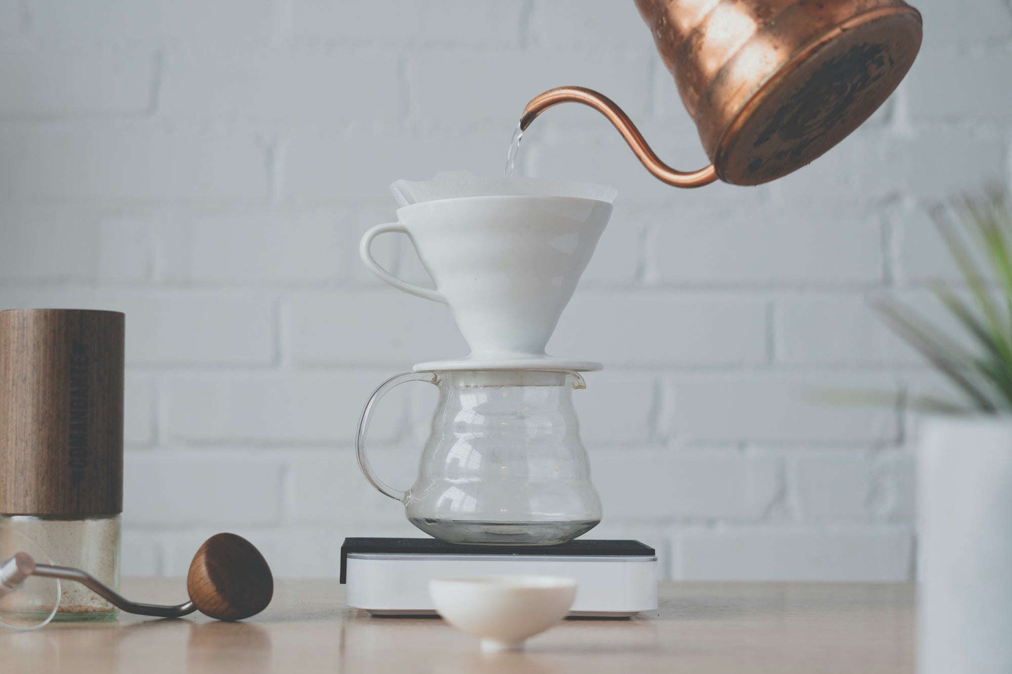 A V60 brewer on a carafe with water being poured into to to brew coffee