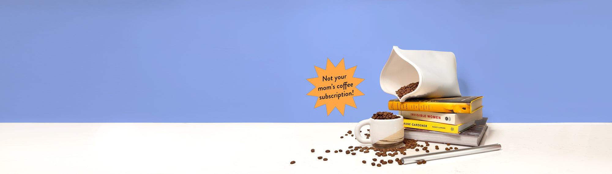 A styled still life with a Zero-Waste Coffee Club reusable bag pouring coffee beans into a small white mug, with more beans scattered on a white surface. A stack of books sits beneath the bag.