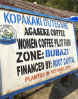 Signboard with text about Agaseke Coffee Women Coffee Pilot Farm in Kopakaki Dutegure, financed by Root Capital.