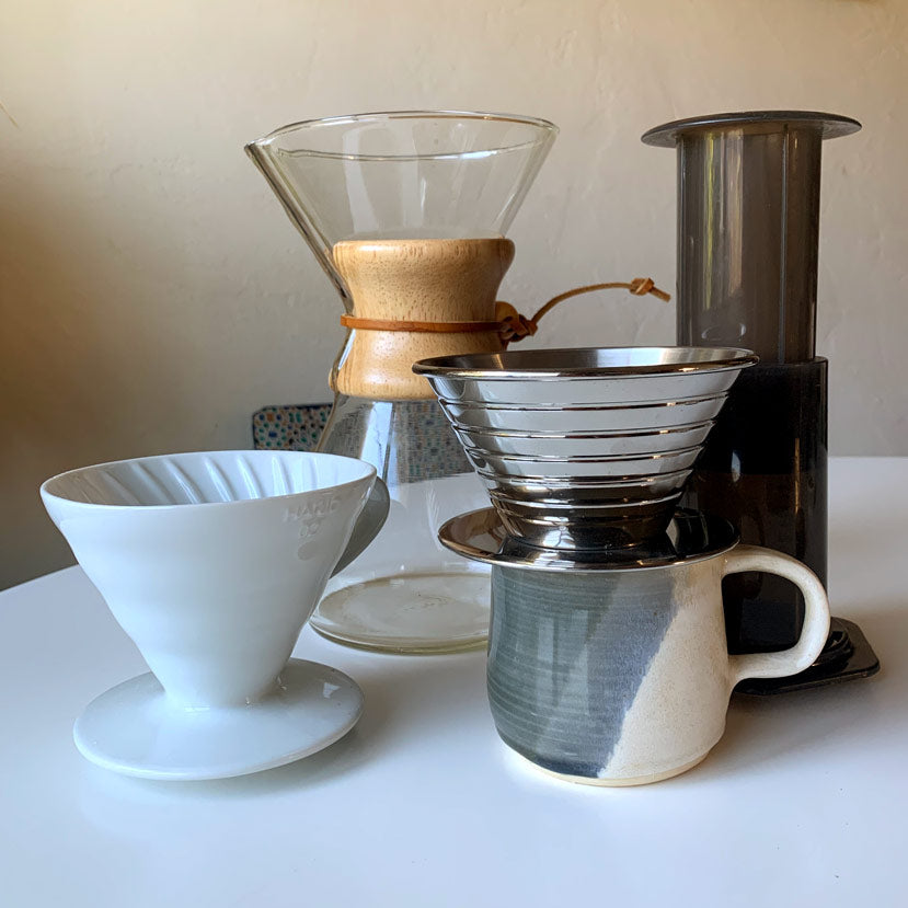 A collection of coffee brewers that are easy to use at home on a white table with 1 mug